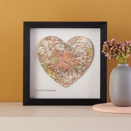 Map heart mounted on white card and framed in black box frame.
