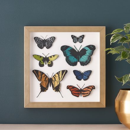 Seven metallic paper cut butterflies on white mount in gold wood box frame.