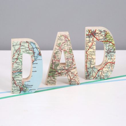 Solid wood letters D A D faced in map standing on mantelpiece.