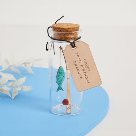 Miniature engraved fishing rod and fish inside a glass message  bottle.