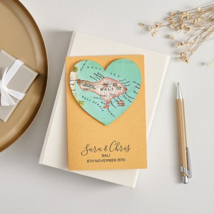 Gold wedding card with script font and a map of bali. Gold oen and dried  flowers