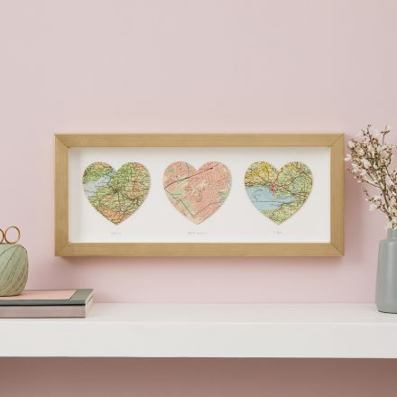 Three personalised map hearts in gold frame, landscape orientation. Hanging above mantelpiece.