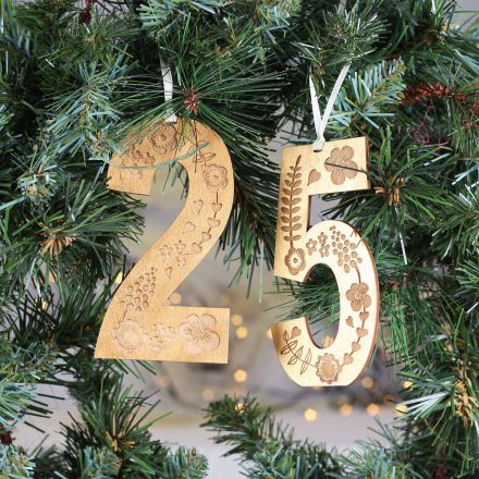 Wooden numbers, engraved with decorative floral design and painted in gold. Strung on cream ribbon and hung on Christmas wreath.