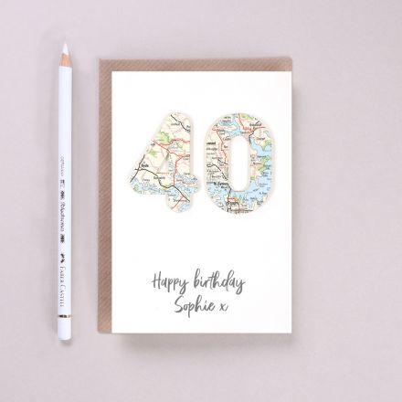 Personalised special age birthday card featuring '40' cut from map and 'happy birthday Sophie' printed below. Card lying on brown envelope.