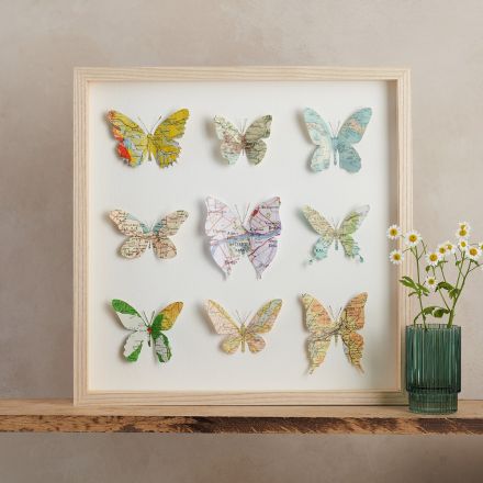 nine papercut map butterflies in a light wood box frame 