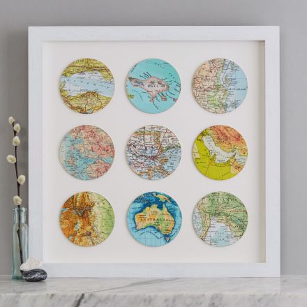 Nine personalised map locations circles framed in white wood box frame and sat on marble mantelpiece
