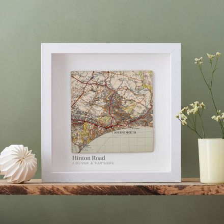 Square map of Bournemouth framed in white box frame on shelf.