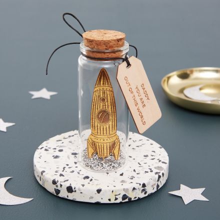 Miniature handpainted wooden rocket dropped inside glass bottle.