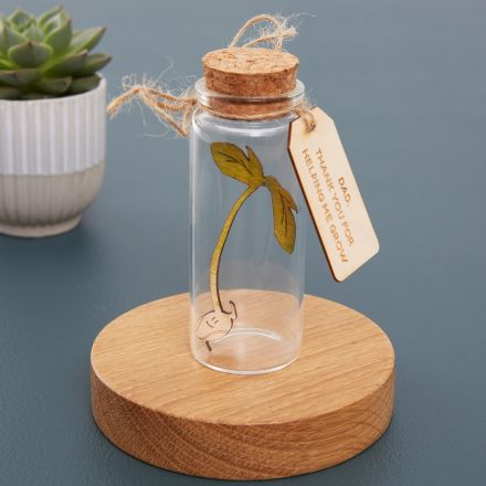 Tiny handpainted seedling cut from wood inside glass bottle.