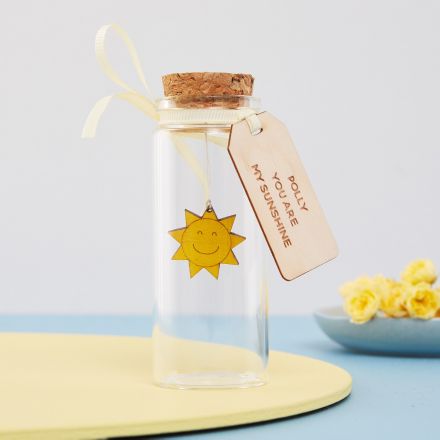 Engraved sunshine suspended in miniature glass message bottle.