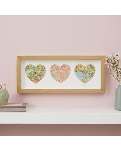 Three personalised map hearts in gold frame, landscape orientation. Hanging above mantelpiece.