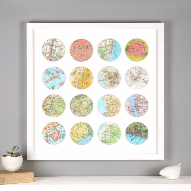 Sixteen map location circles mounted in white wood frame above white mantelpiece.