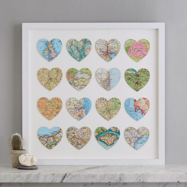 Sixteen personalised map location hearts in white box frame on marble mantelpiece