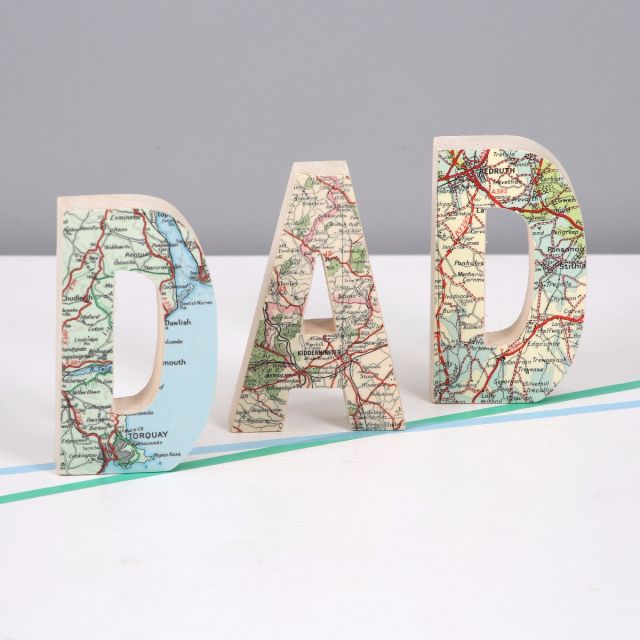 Solid wood letters D A D faced in map standing on mantelpiece.