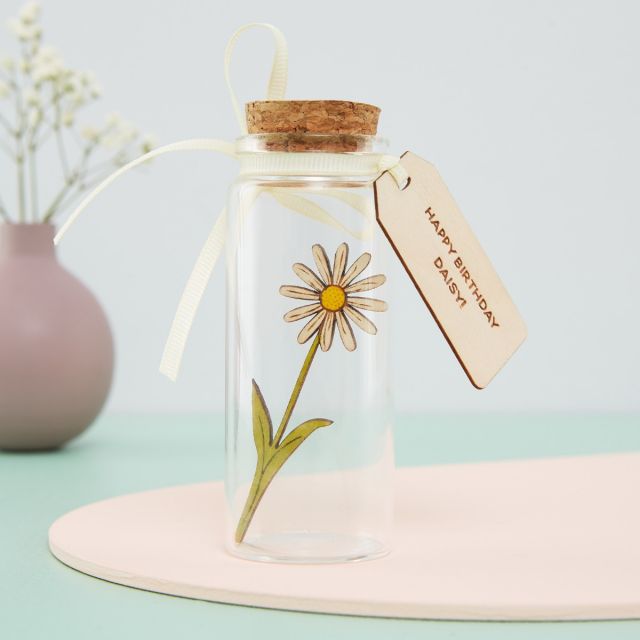 Miniature daisy in a glass bottle with engraved message tag.