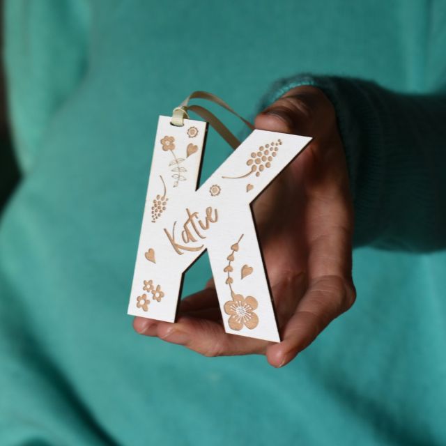 Engraved wooden letter keepsake decoration. Letter A, strung with cream ribbon and hanging on Christmas wreath with Amelia engraved on the front.