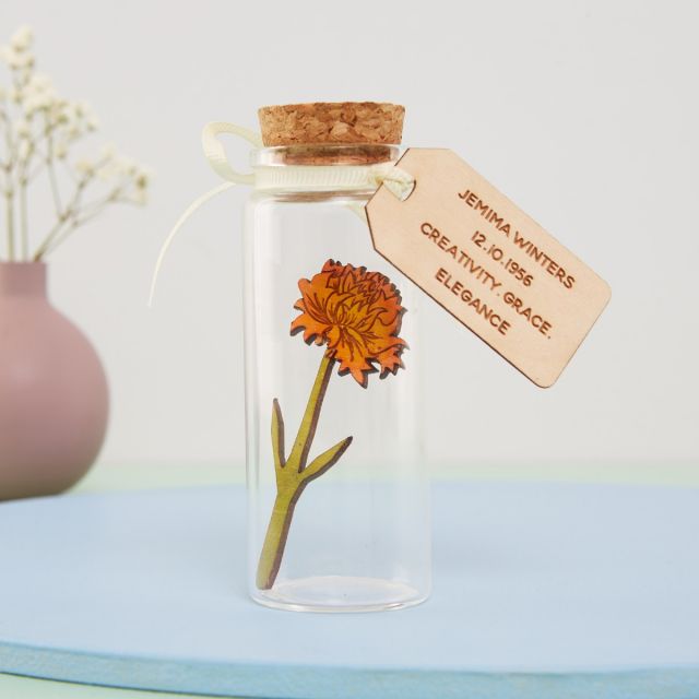Miniature marigold in a glass bottle with engraved message tag.