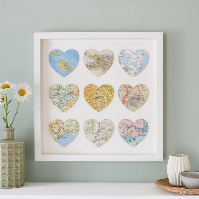 Nine map hearts mounted on white card in white wood box frame.