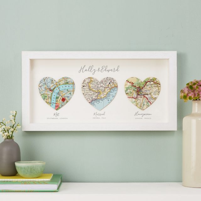 Three map hearts in white wood frame, landscape orientation. Printed personalisation beneath each heart.